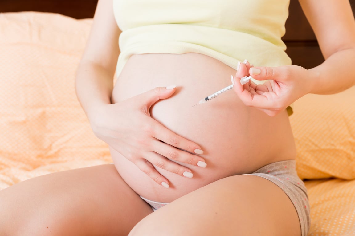 Pregnant Woman with Insulin Syringe in Home on Bed. Pregnant Dia