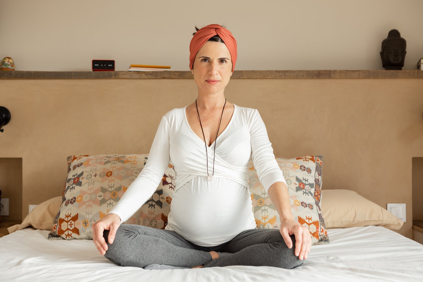 Pregnant chilled out hippie woman in yoga pose looking at camera